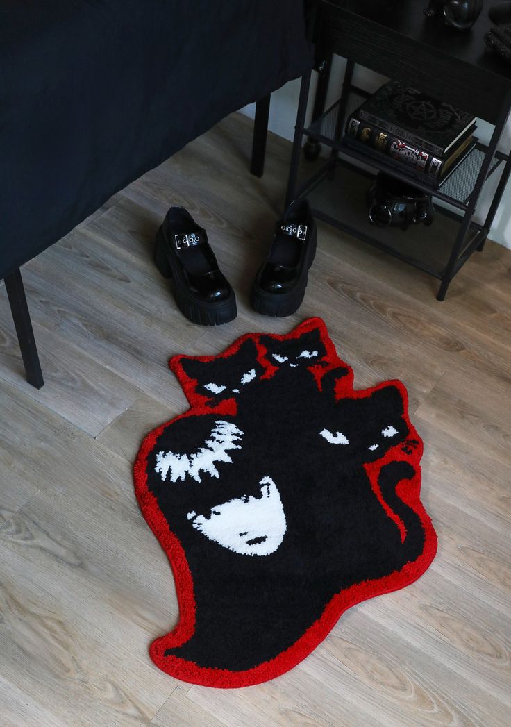 a pair of black and red shoes sitting on top of a wooden floor next to a bed