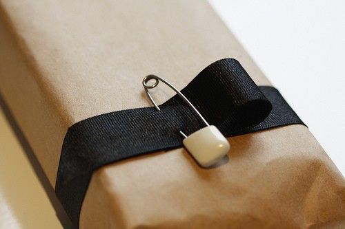 a present wrapped in brown paper with a black ribbon and white candle on the top