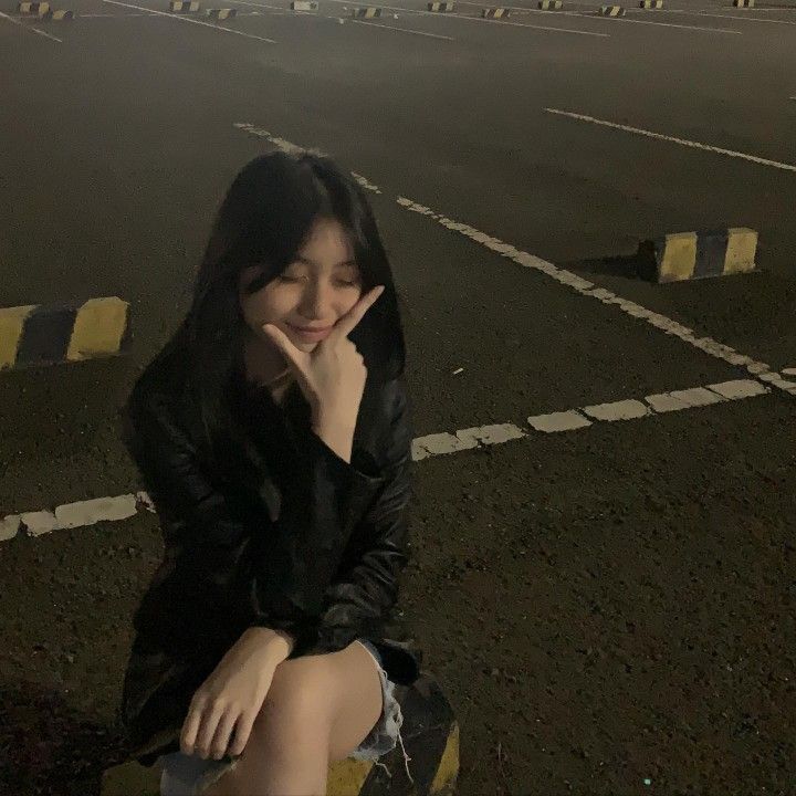 a woman sitting on top of a parking lot next to a yellow fire hydrant