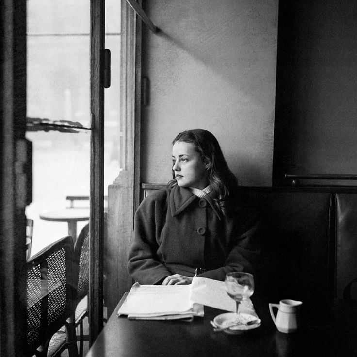 a black and white photo of a woman sitting at a table