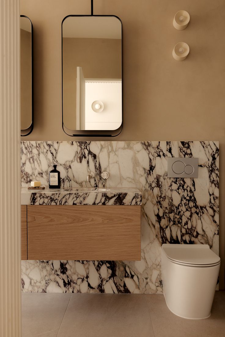 a bathroom with a toilet, sink and mirror on the wall next to each other