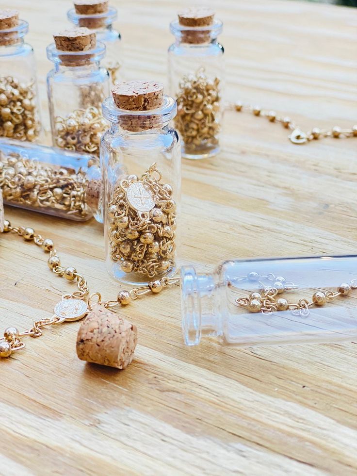 several glass bottles filled with different types of beads and corks on a wooden table