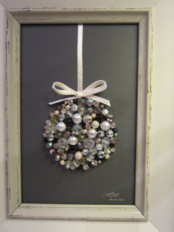 a christmas ornament hanging in a frame with a ribbon on it's side