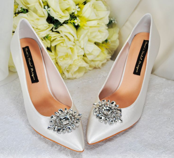 a pair of white high heel shoes next to a bouquet of flowers