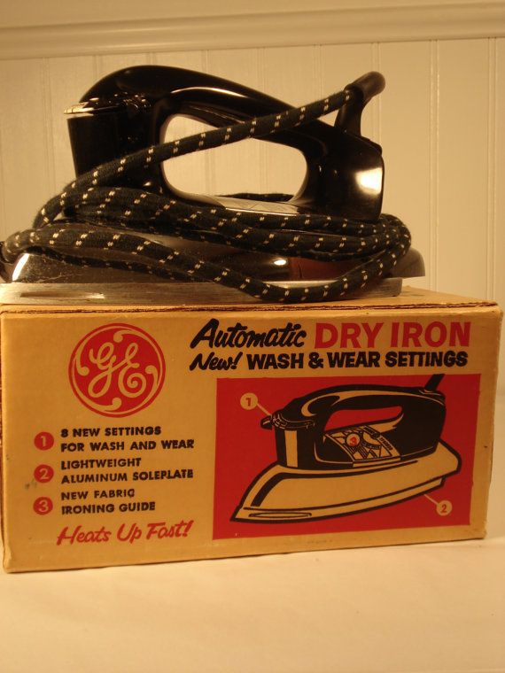 an old black iron sitting on top of a box next to it's packaging