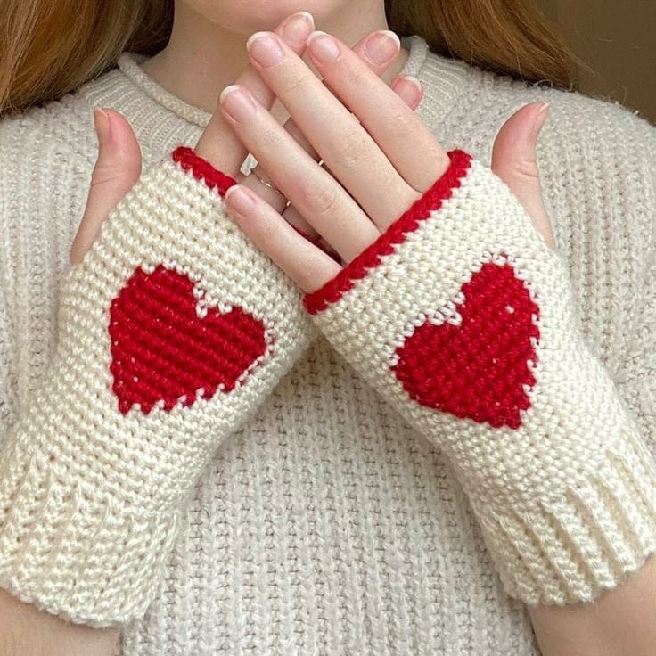 a close up of a person wearing knitted gloves with hearts on the palm and fingers