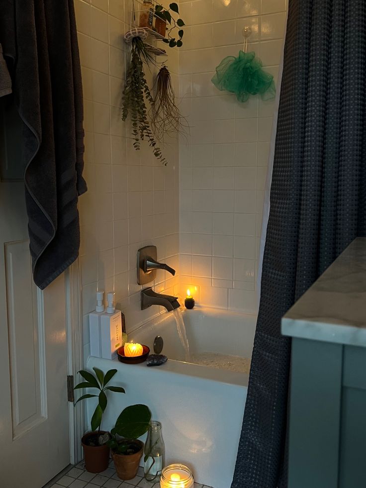 a bathtub with candles in it next to a potted plant