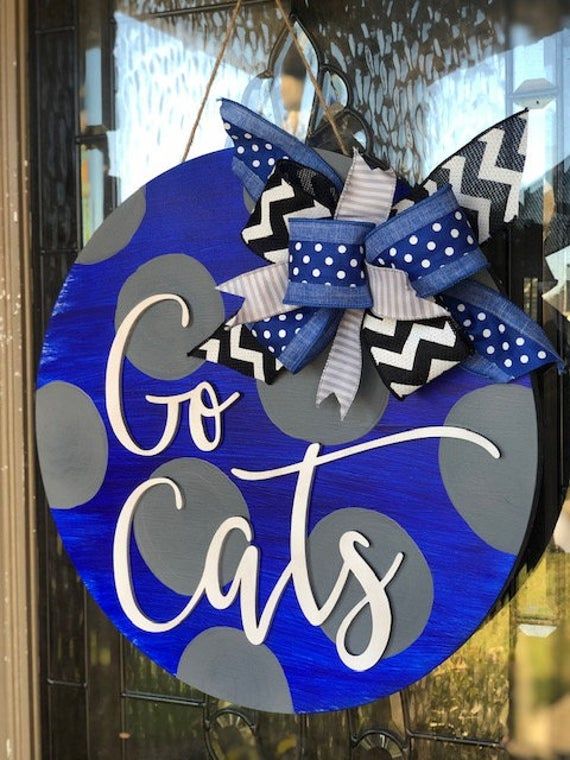 a blue and white door hanger with the words go cats written on it in front of a window