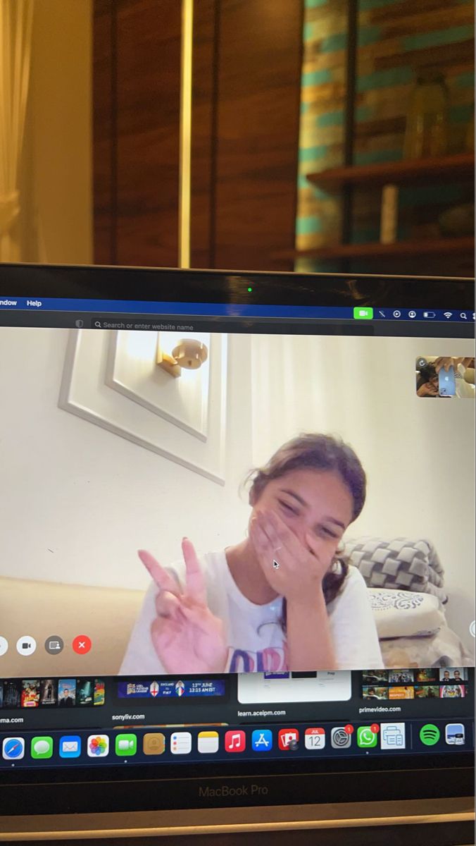 a laptop computer screen with a girl making the peace sign on it's face