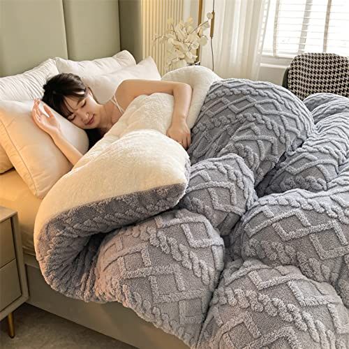 a woman laying on top of a bed covered in blankets and pillows next to a window