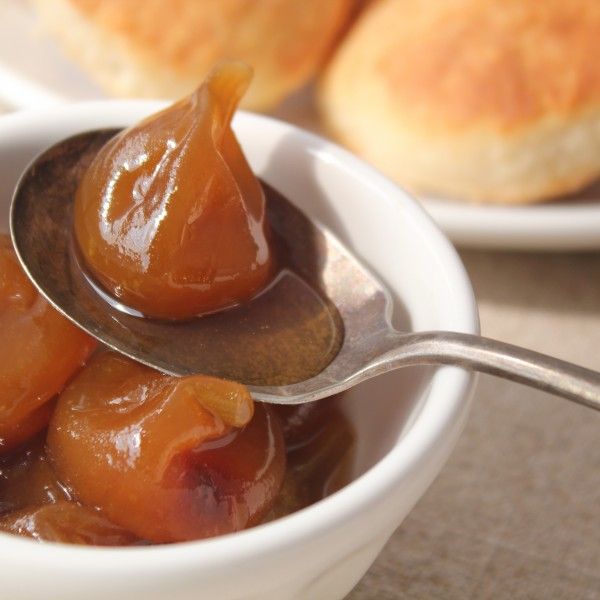 a spoon with some food in it on top of a table next to bread rolls