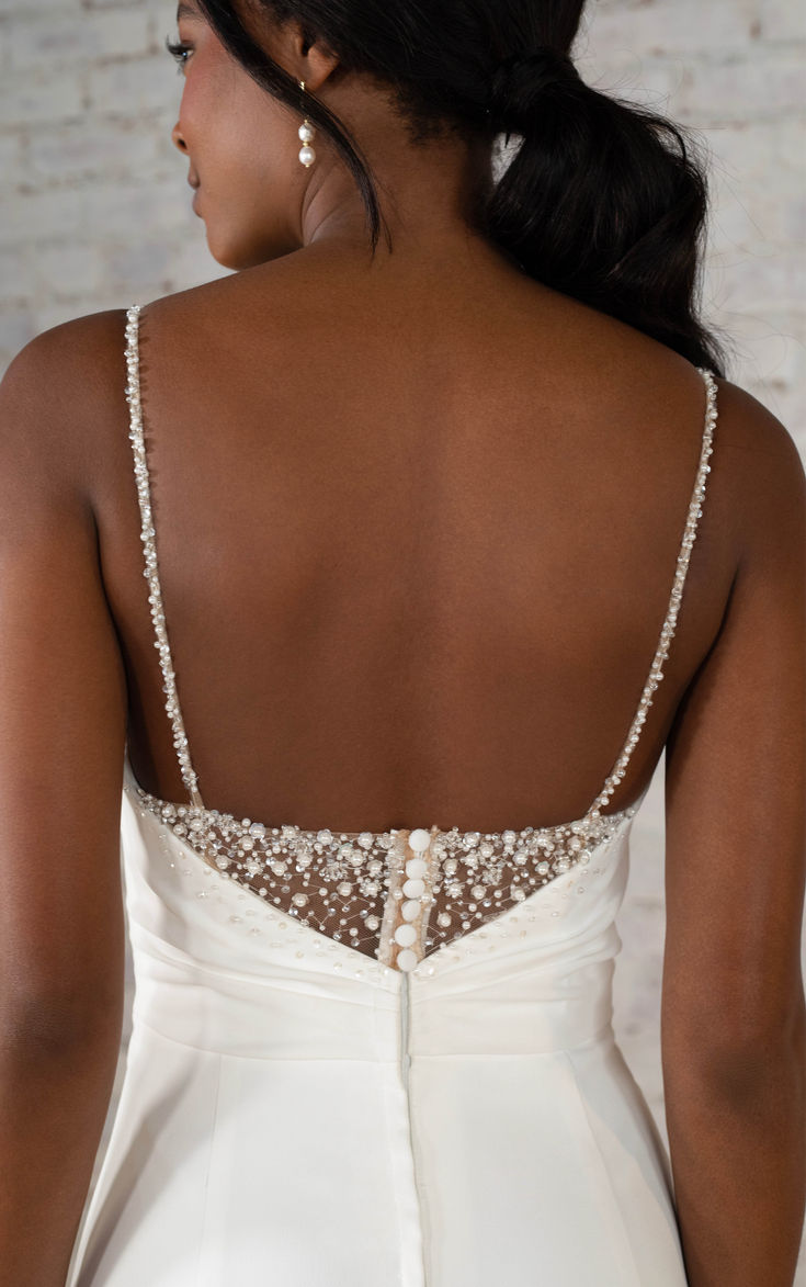 the back of a woman's wedding dress with beading on her neck and shoulders