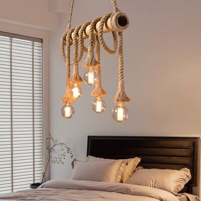 a bed with white sheets and pillows under a chandelier hanging from the ceiling