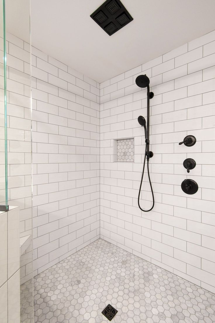 a white tiled bathroom with black fixtures and hexagonal floor tiles on the walls