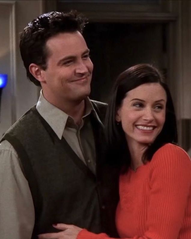 a man and woman standing next to each other in front of a tv screen smiling