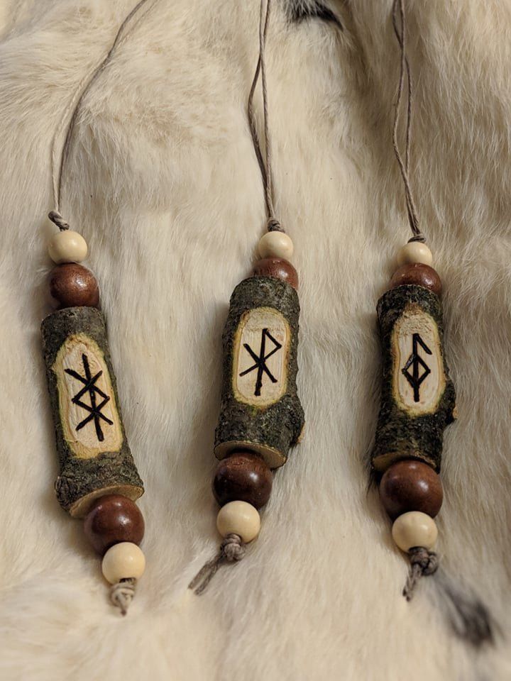 three wooden beads with arrows on them are hanging from a white fur covered surface,