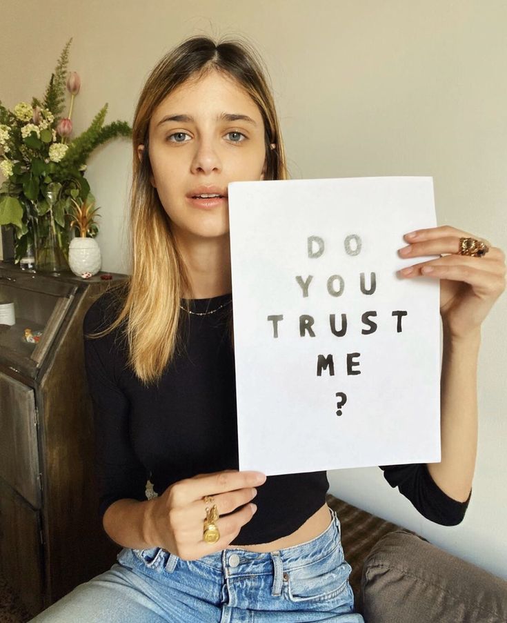 a woman holding up a sign that says do you trust me?