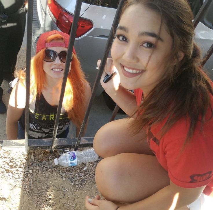 two young women sitting next to each other in front of a car