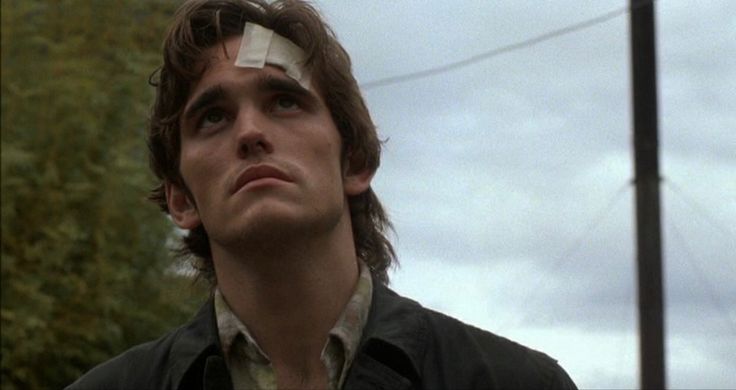 a young man with tape on his forehead looking up at something in the sky behind him