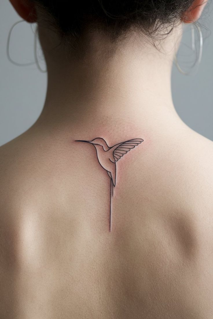 the back of a woman's neck with a hummingbird tattoo on it