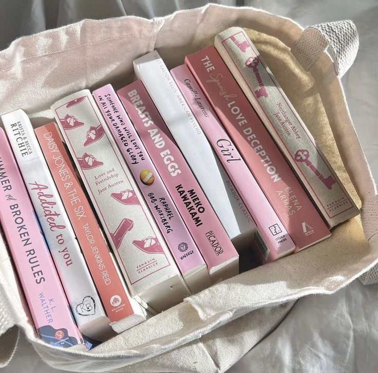 a bunch of books that are sitting in a bag on a bed with white sheets