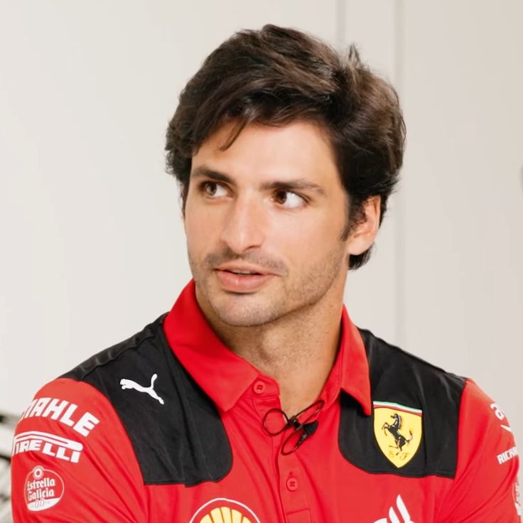 a man wearing a red and black shirt looking at the camera with a serious look on his face