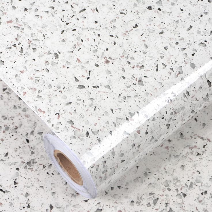 a roll of toilet paper sitting on top of a white floor covered in speckles