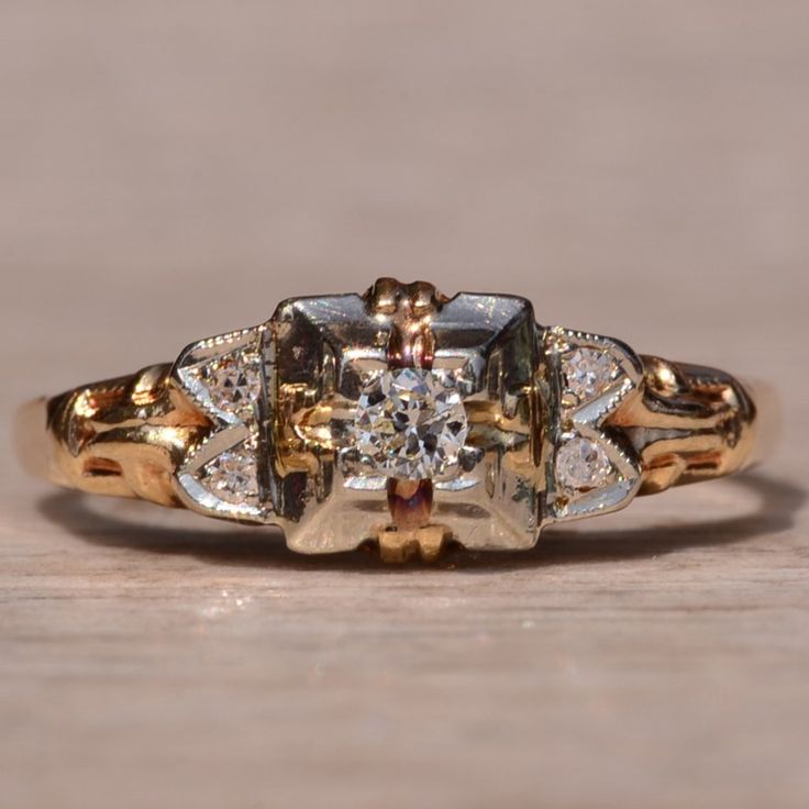 an antique diamond ring is shown on a wooden surface