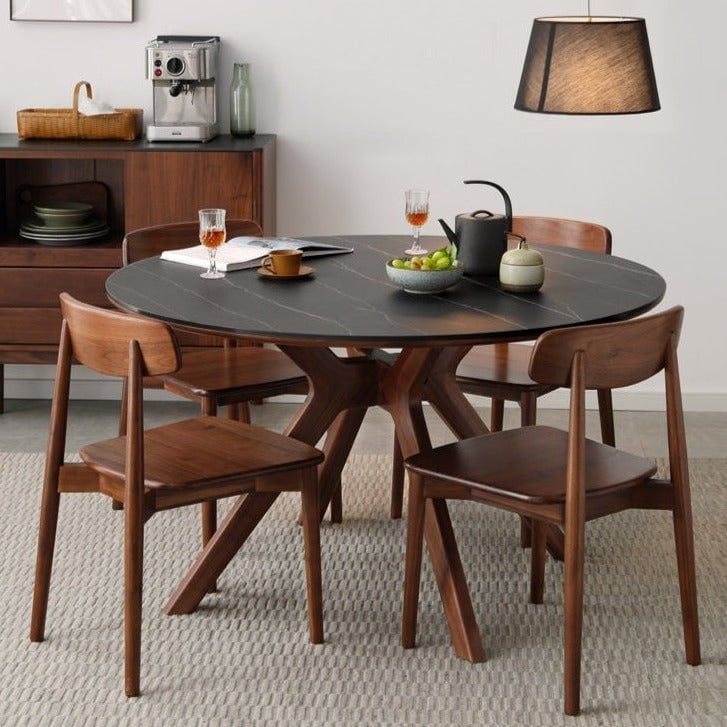 a dining room table with four chairs and a bowl of fruit on the table next to it