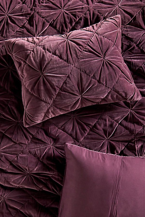 a bed with purple sheets and pillows on top of it, next to a pillow