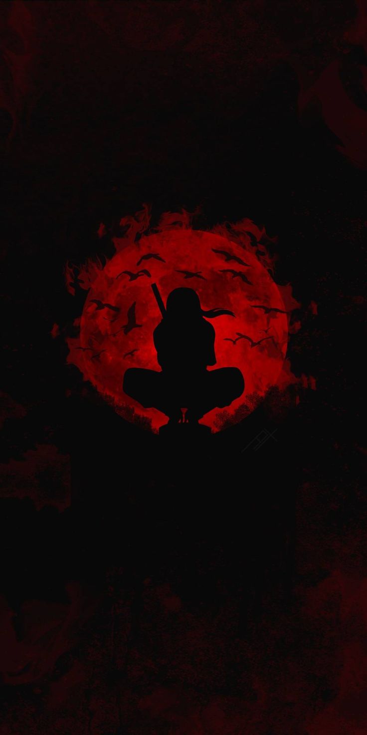 the silhouette of a person sitting in front of a red moon