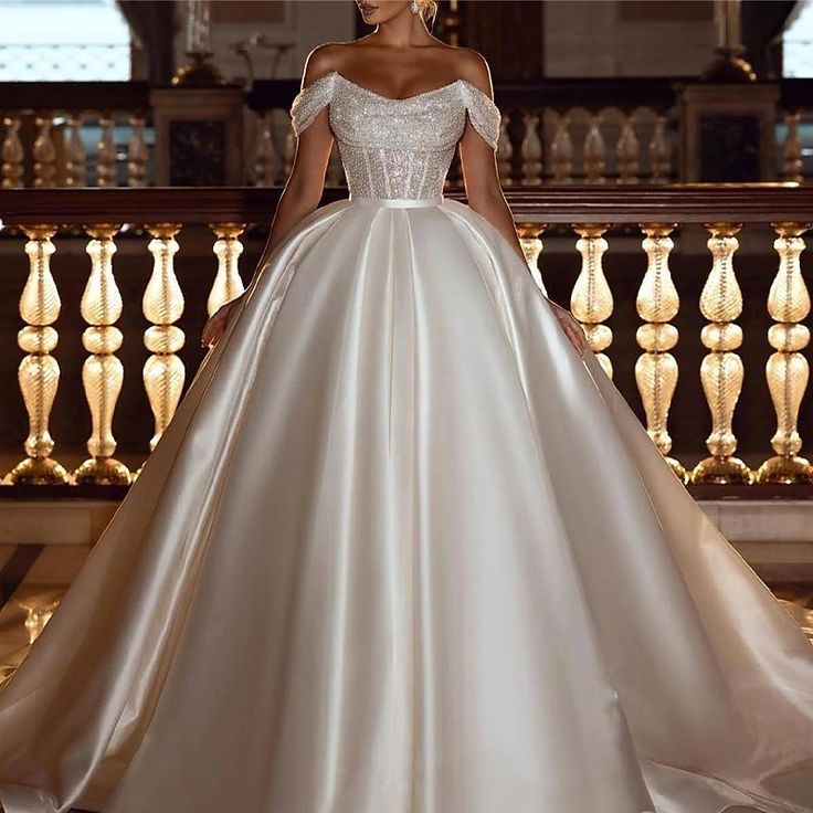 a woman in a white wedding dress standing on a balcony with her hands on her hips