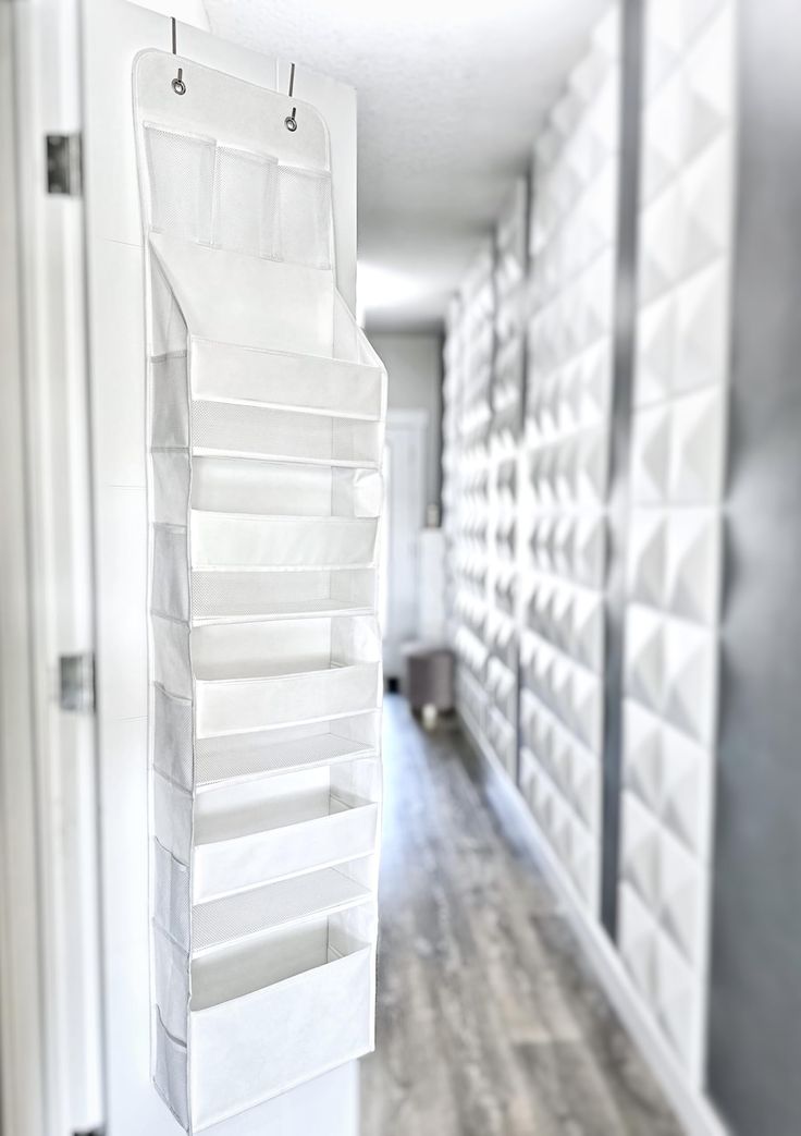 an empty hallway with white storage bins hanging on the wall and wood flooring