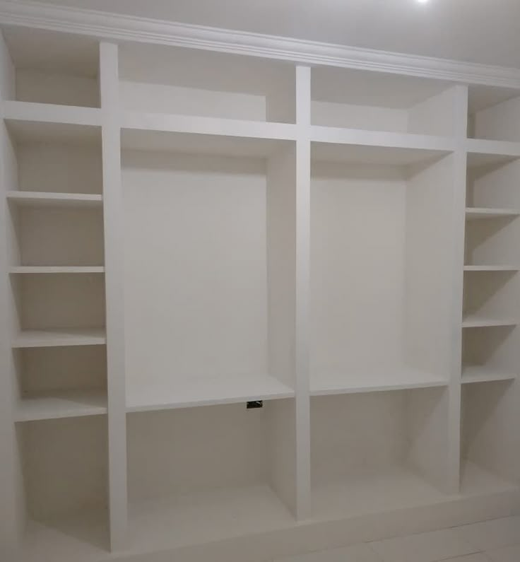 an empty white bookcase in a room with no one on the shelves or doors