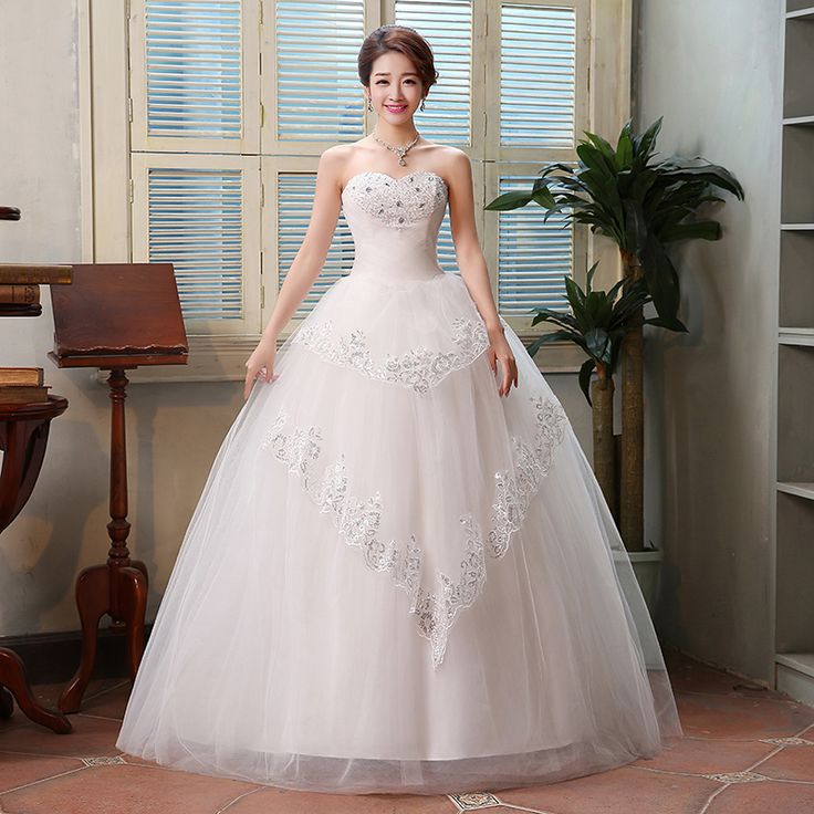 a woman in a white wedding dress standing on a tile floor next to a window