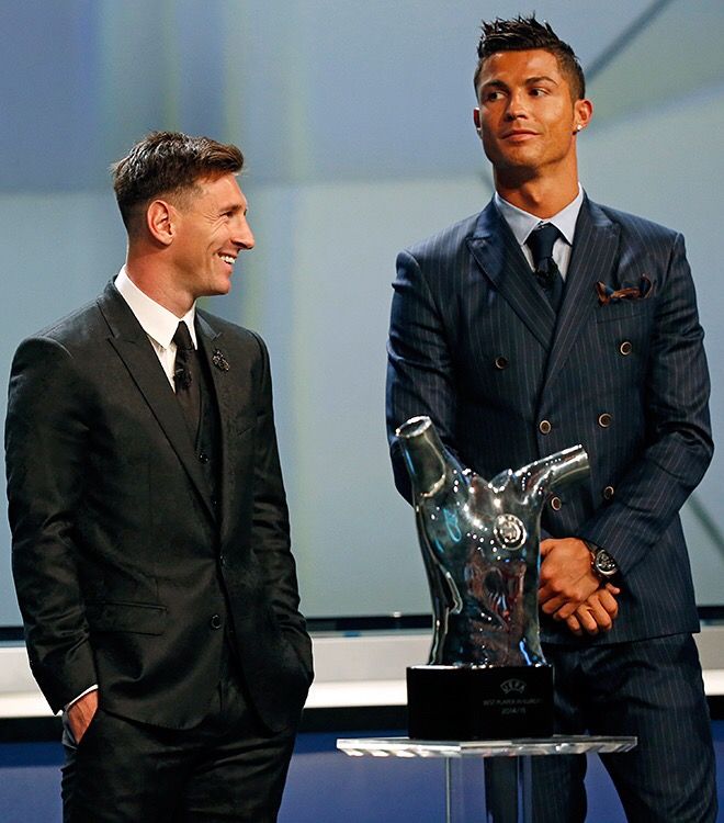 two men standing next to each other in front of a glass trophy on a table