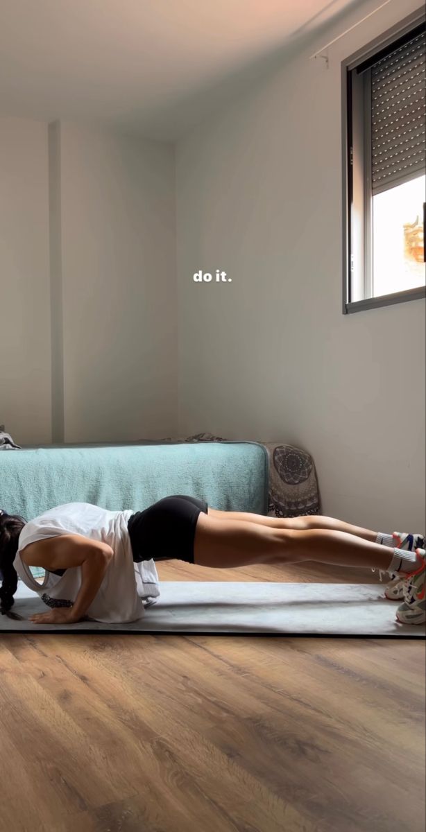 a man and woman doing yoga on mats in a room with wood floors, windows, and a couch