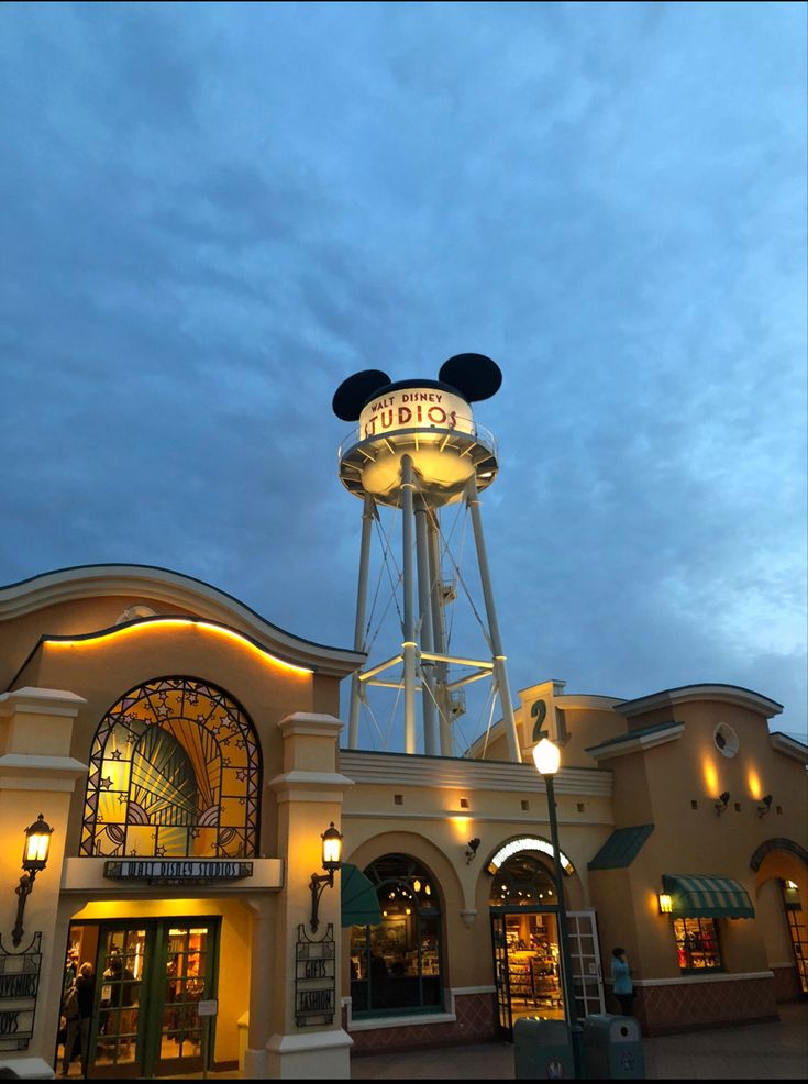 the entrance to mickey mouse's kingdom at night with its water tower in the background