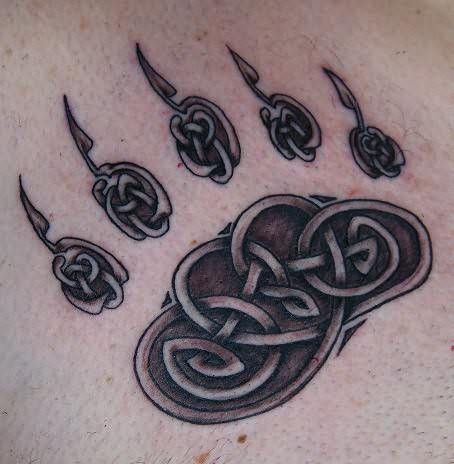 a man with a tattoo on his chest that has an animal's paw in it