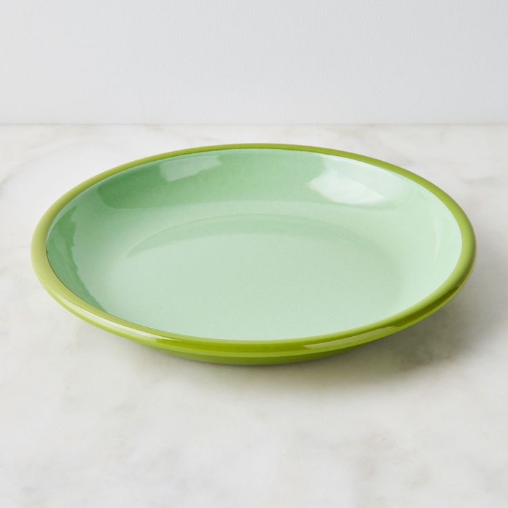 a green bowl sitting on top of a white counter