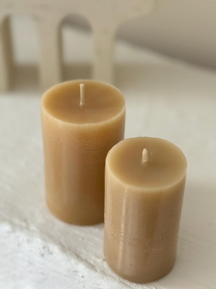 two candles sitting next to each other on top of a white cloth covered tablecloth