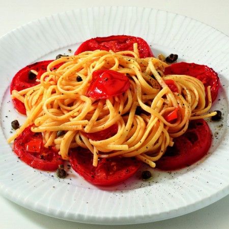 a white plate topped with spaghetti and tomatoes