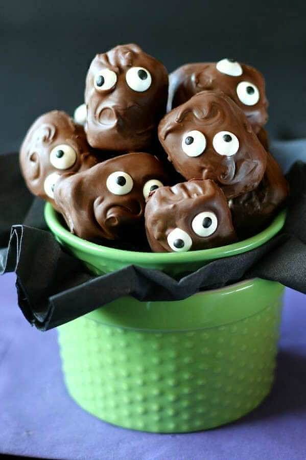 chocolate covered cookies with googly eyes in a green bowl