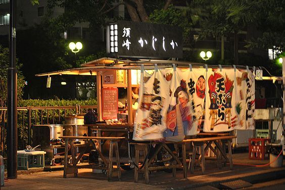 an outdoor market with towels hanging outside at night