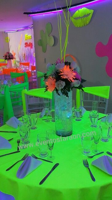 the table is set for an event with neon green linens and flowers in a vase