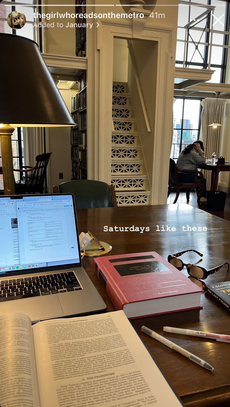 an open book sitting on top of a wooden table next to a laptop computer and notebook