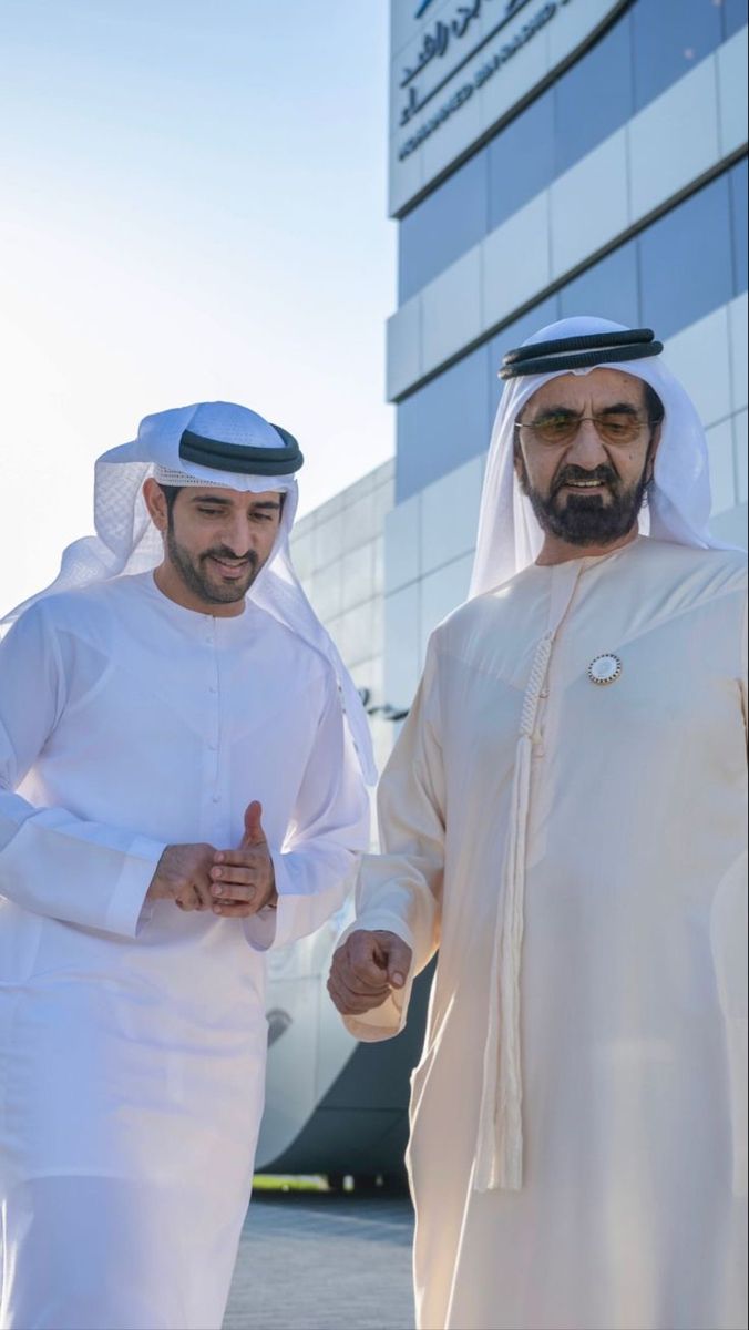 two men standing next to each other in front of a building