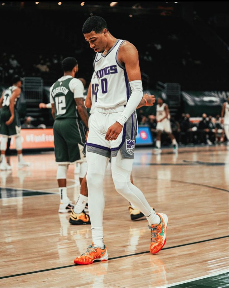 a basketball player walking on the court with his foot in the air and other players behind him