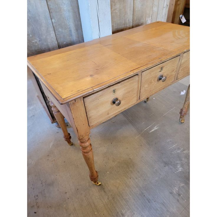 an old wooden table with two drawers on one side and three legs on the other