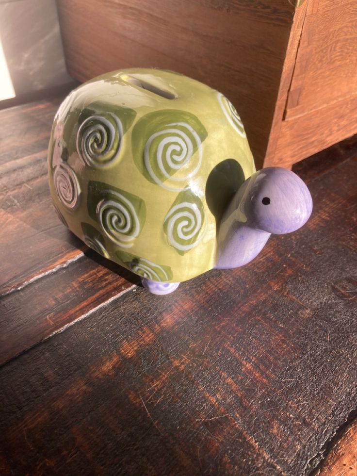 a ceramic turtle figurine sitting on top of a wooden table next to a drawer